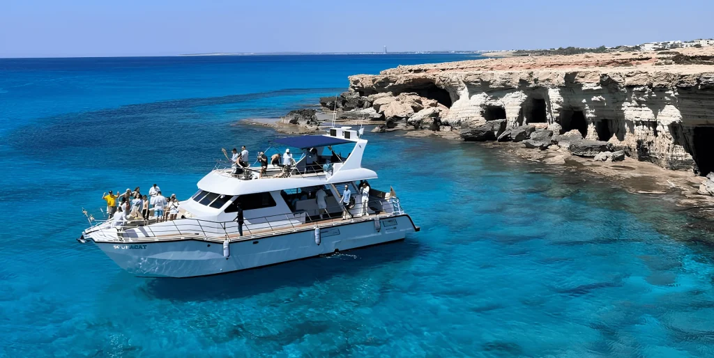 SCUBACAT catamaran anchored beside the limestone sea caves at Cape Greco, Cyprus